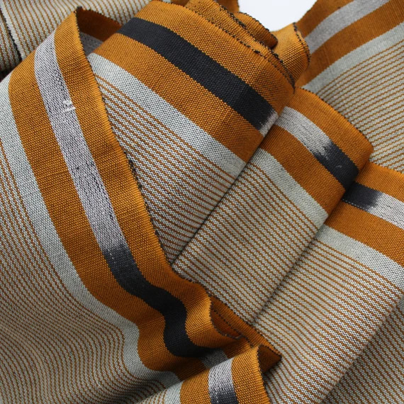 Close-up detail of hand-woven aso oke fabric showing the strip-woven texture