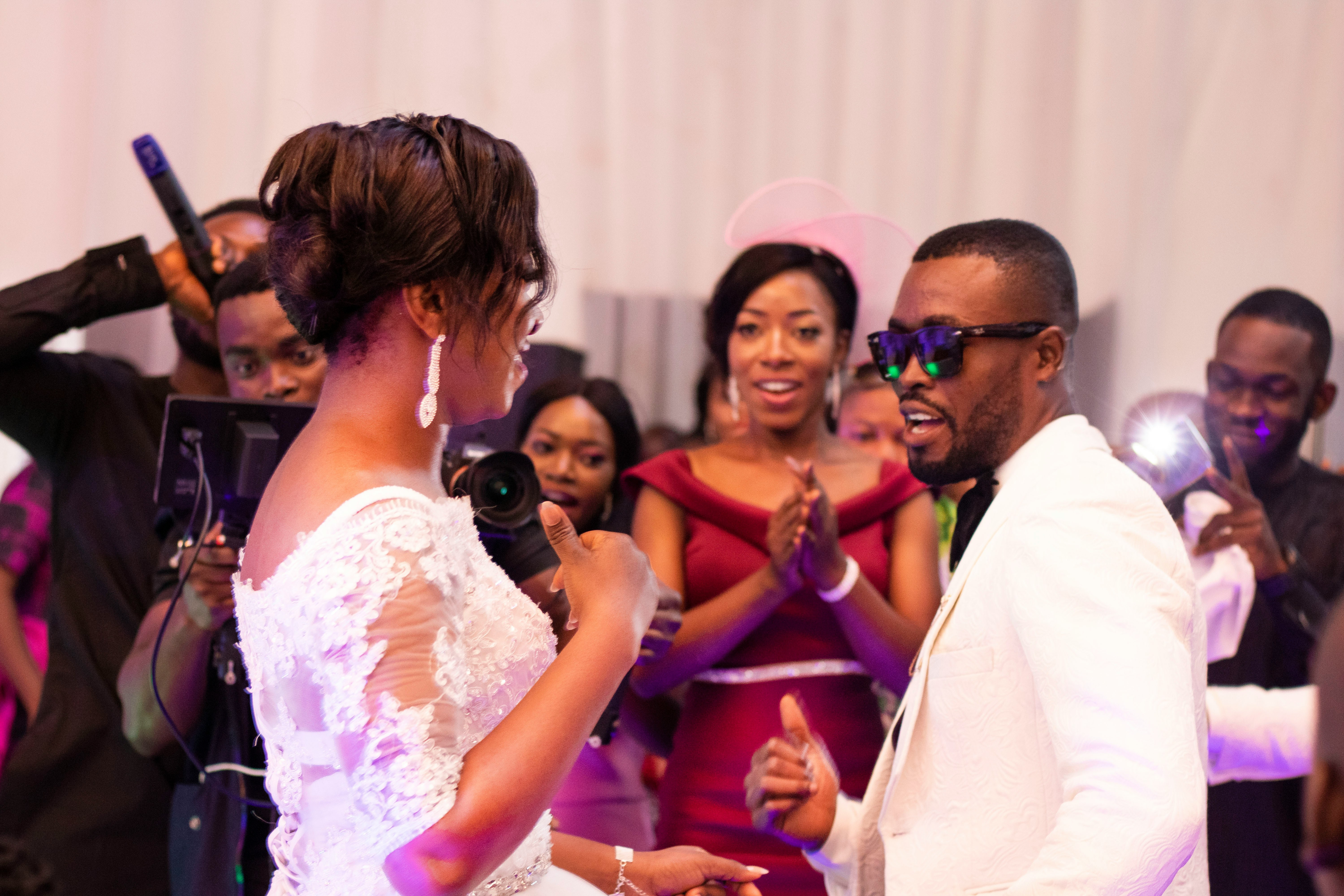 Guests dancing at a Nigerian wedding reception with the DJ visible in the background
