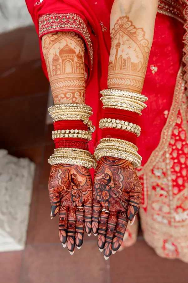 Bride's hands decorated with intricate bridal mehndi designs and gold bangles
