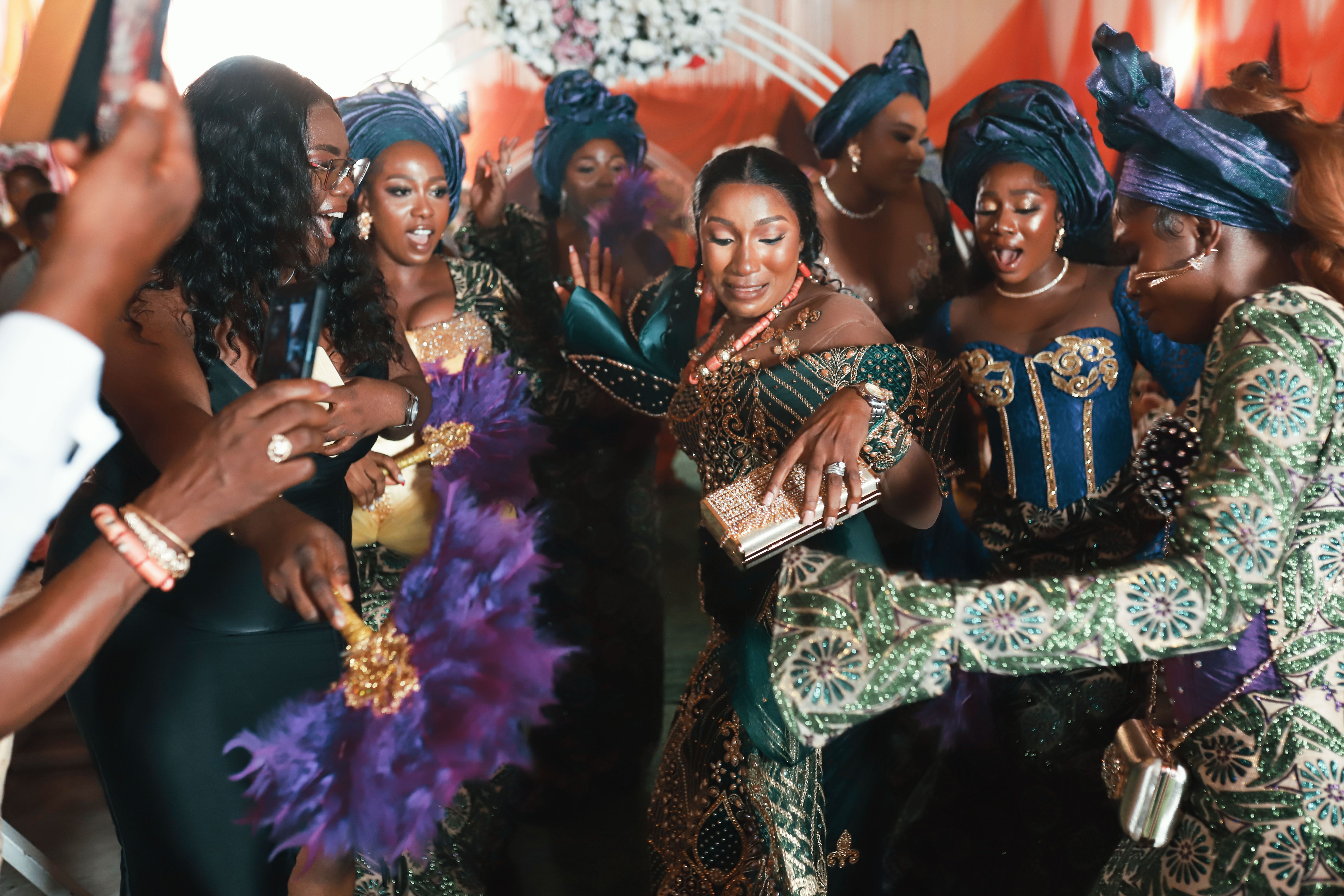 Wedding guests at a Nigerian reception wearing coordinated aso ebi outfits in a range of personal styles