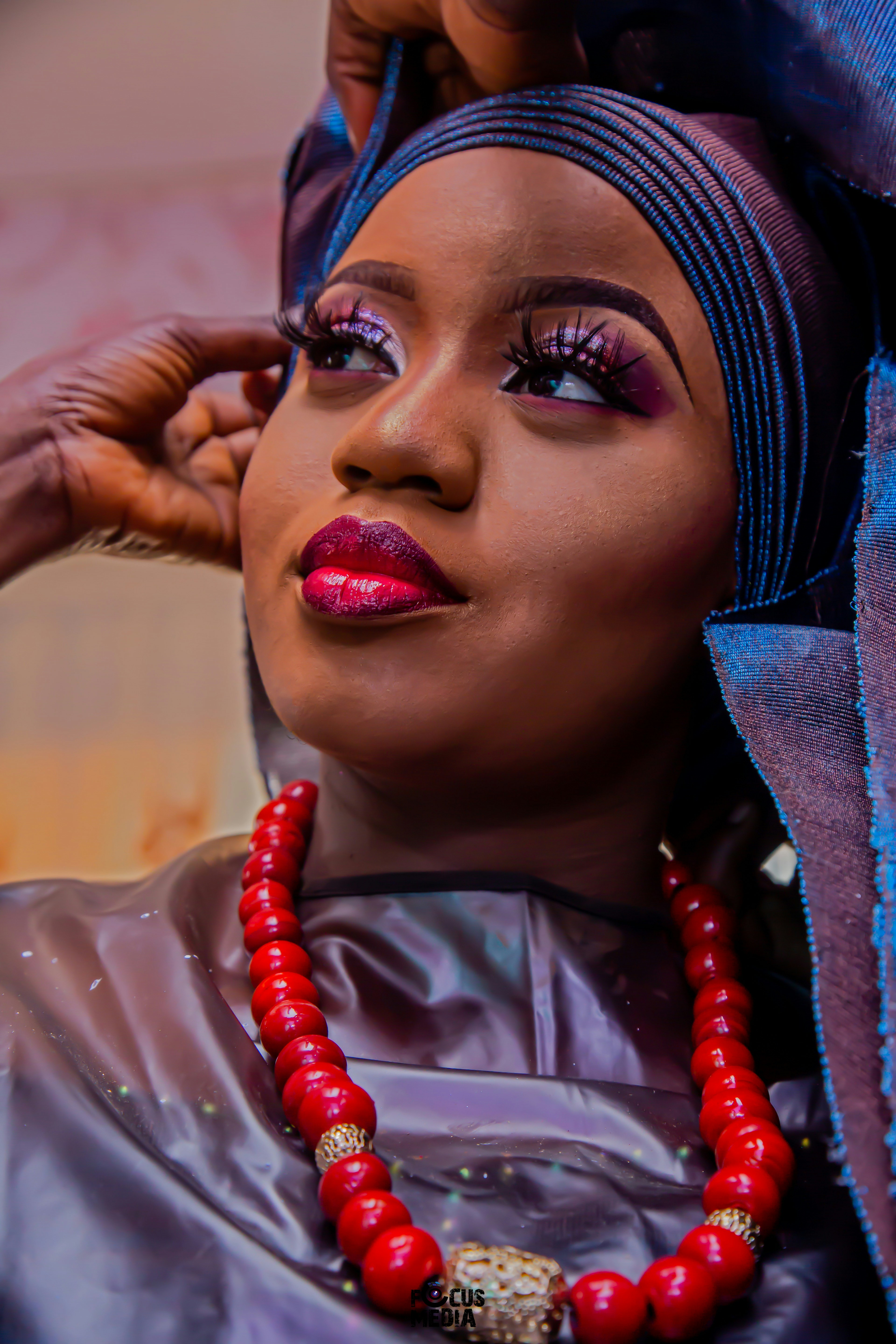 Close-up of a bride with dark skin tone in full bridal makeup, glowing finish, warm tones