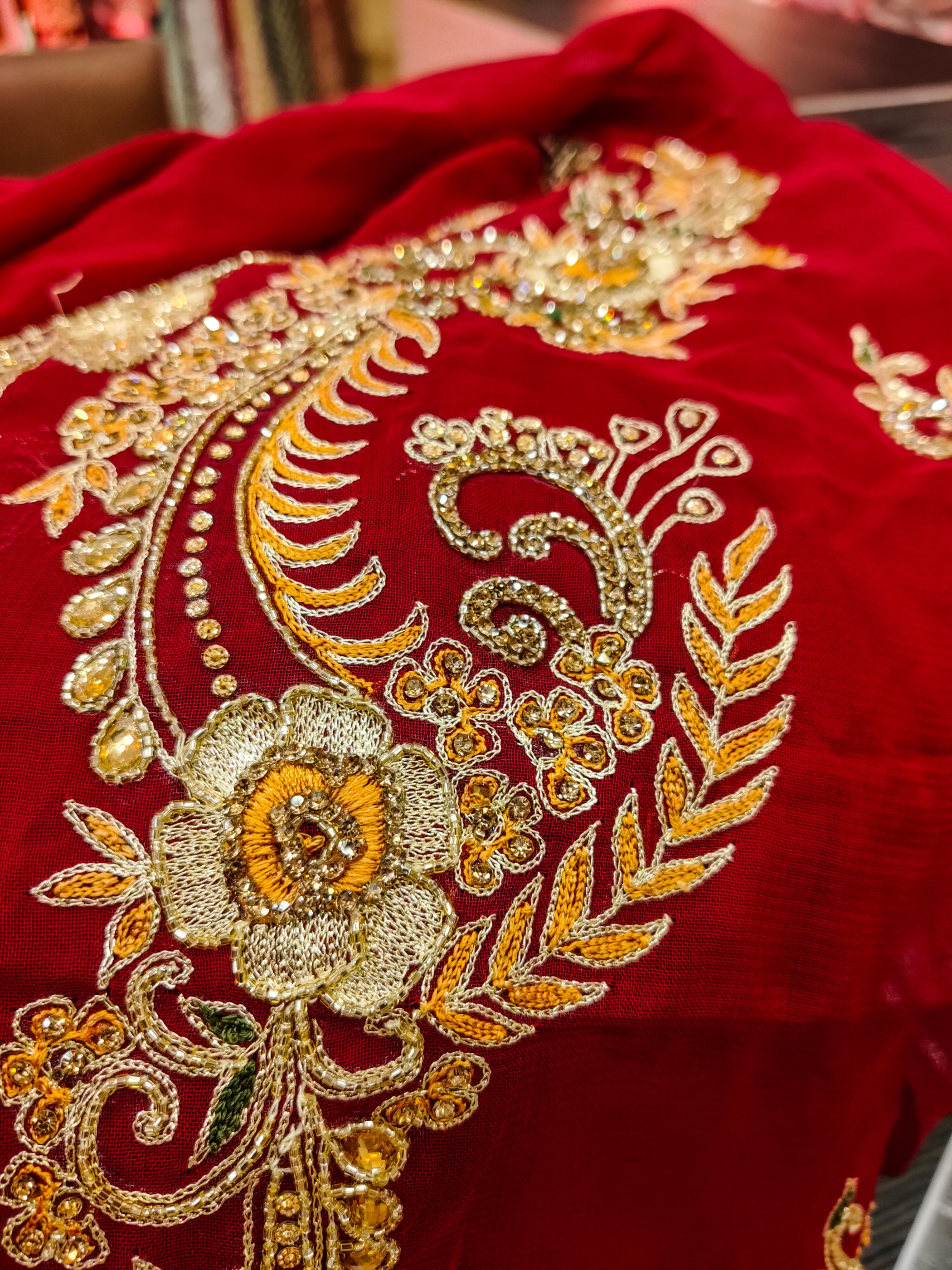 Close-up of intricate zardozi embroidery on red bridal lehenga fabric with gold thread detail