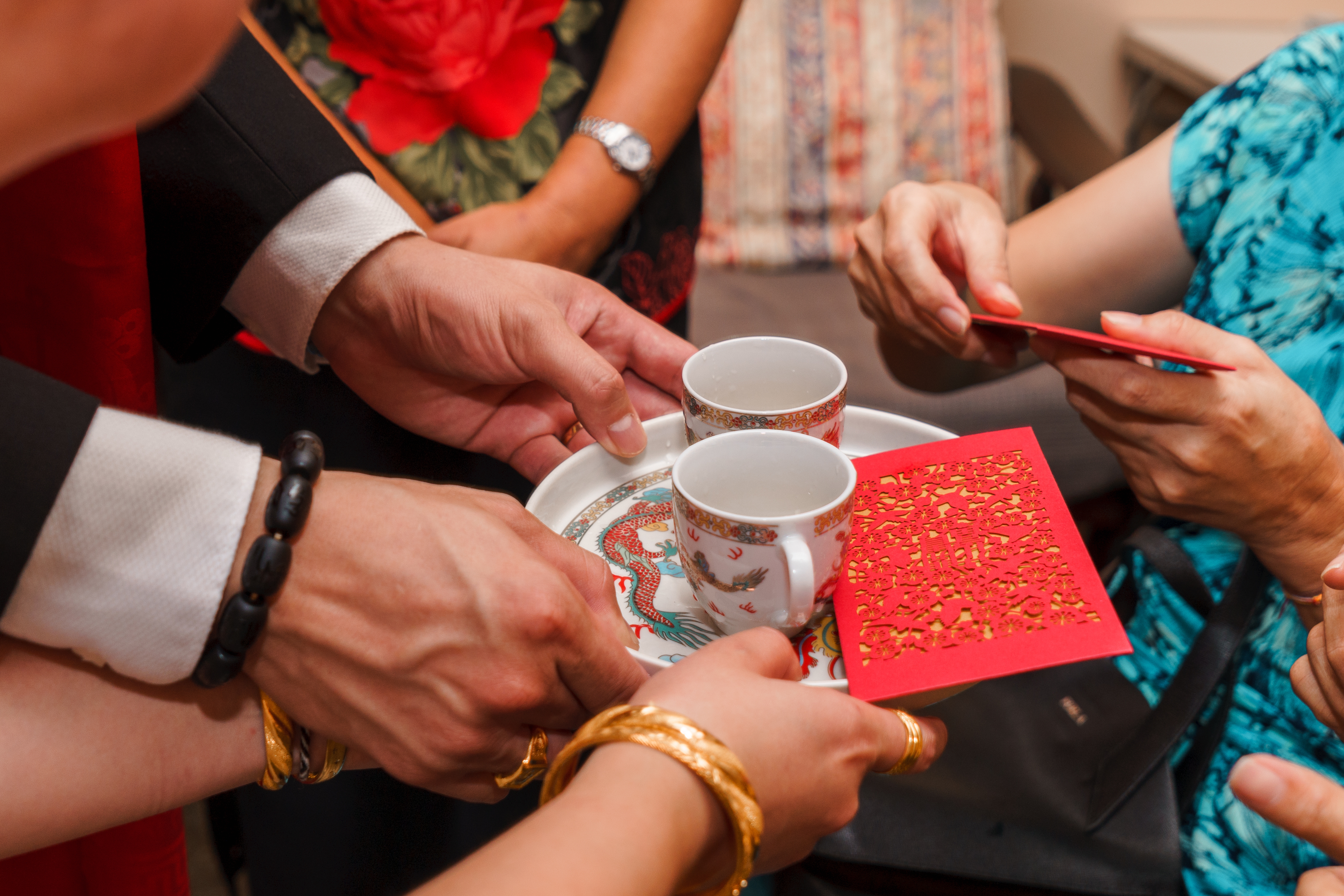 Couple serving tea to parents during a Chinese wedding tea ceremony, kneeling with tea cups presented on saucers