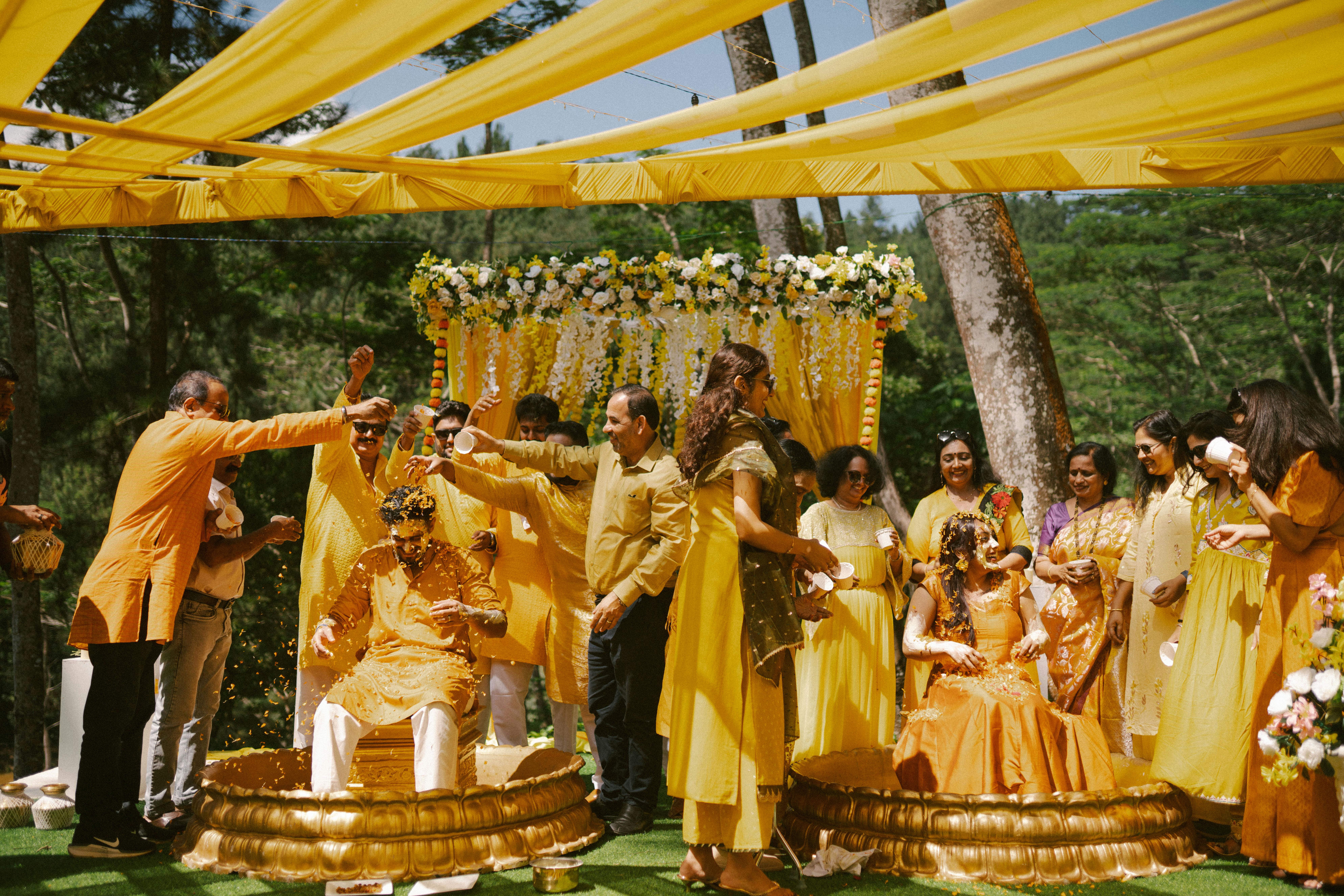 Outdoor haldi ceremony setup with marigold garlands, yellow drapes, floor cushions, and fairy lights
