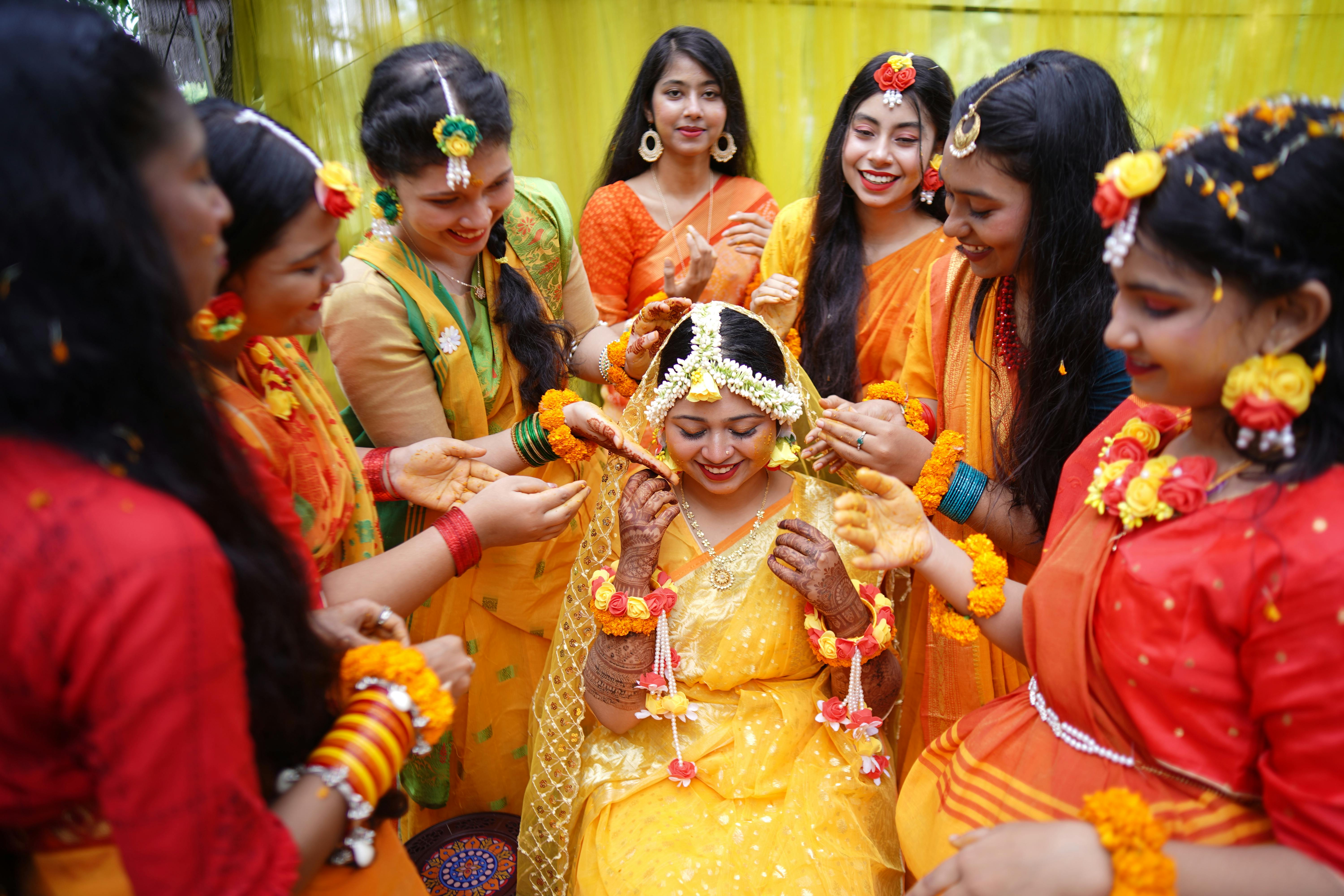 Joyful haldi ceremony moment with family members applying turmeric paste to a smiling bride