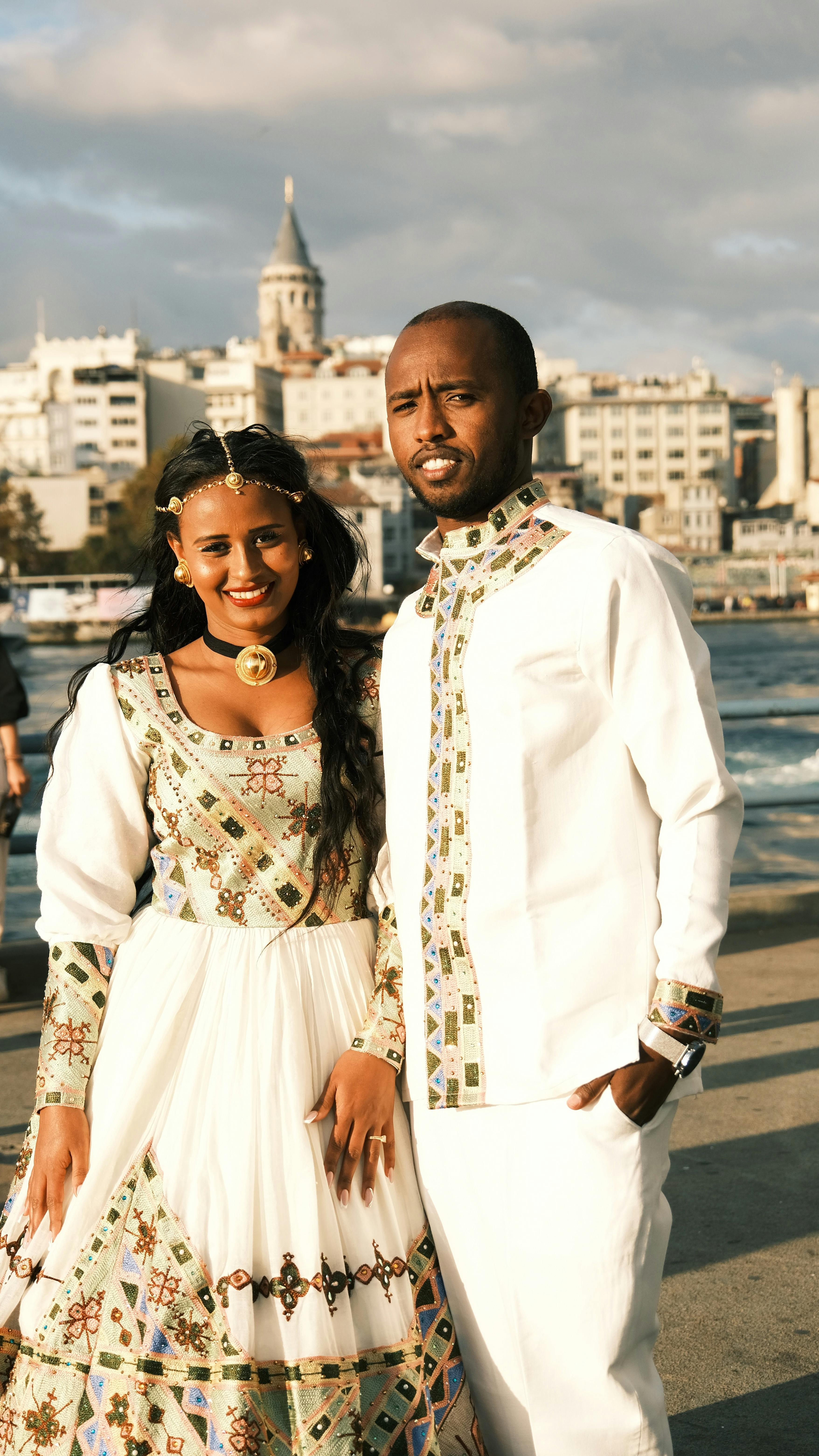 Eritrean or Ethiopian bride in full traditional habesha kemis with gold jewelry and braided hair at a melsi celebration