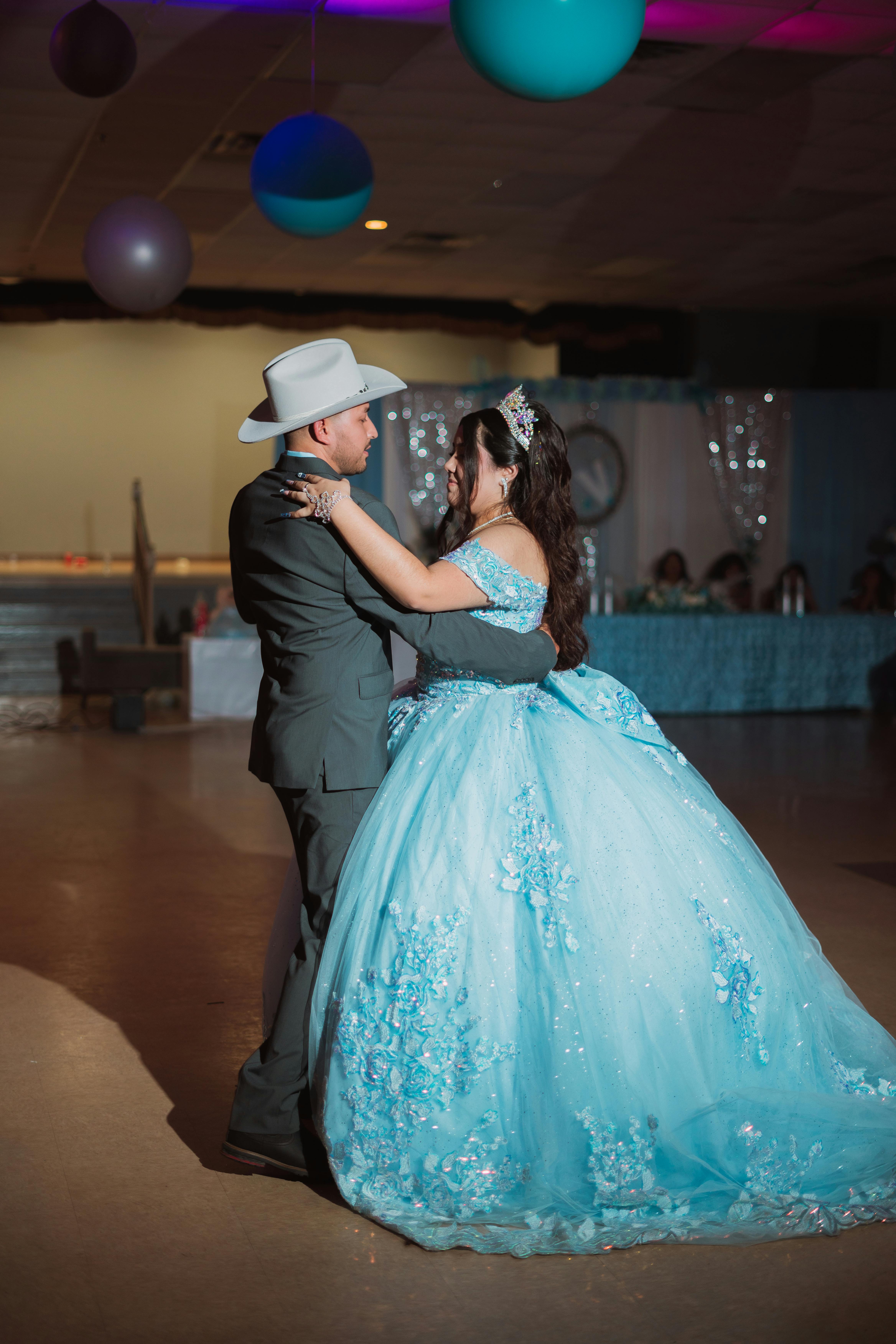 Quinceañera court of honor performing the waltz in coordinating formal attire at a decorated reception