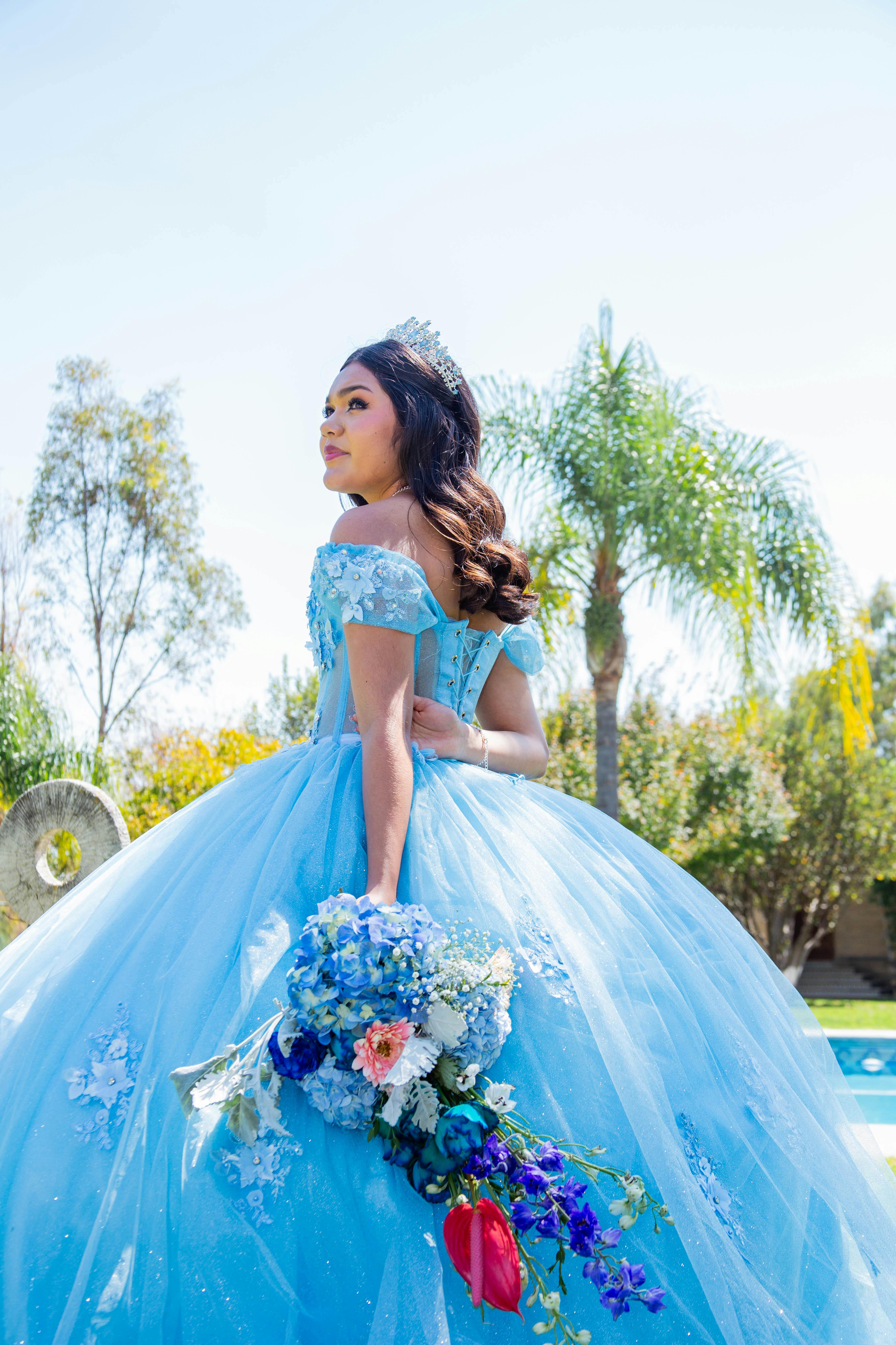 Young woman in an elegant quinceañera ball gown posing for portraits in a garden setting