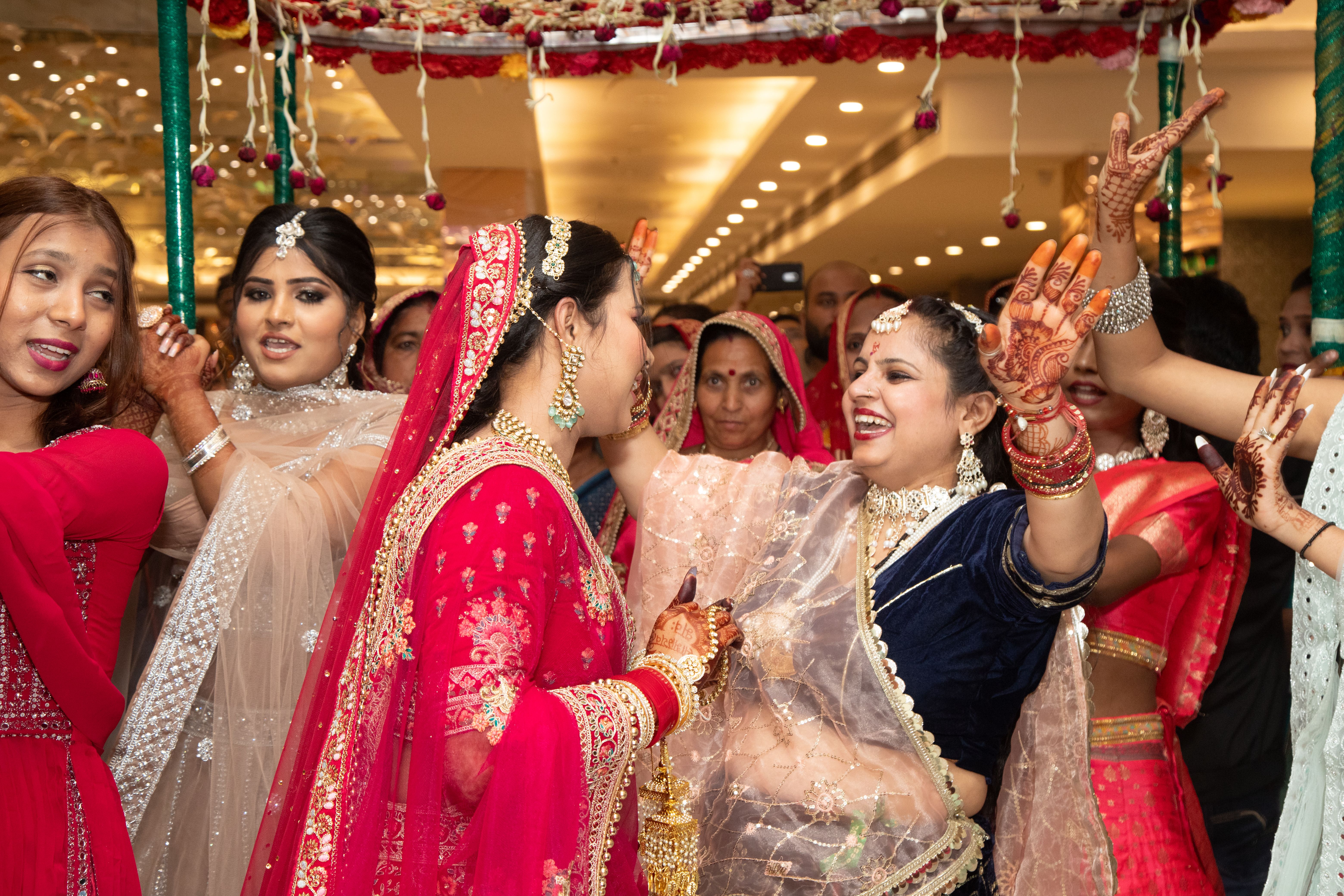 Wide shot of an Indian wedding reception with uplighting, decorated stage, and warm ambient lighting throughout the ballroom