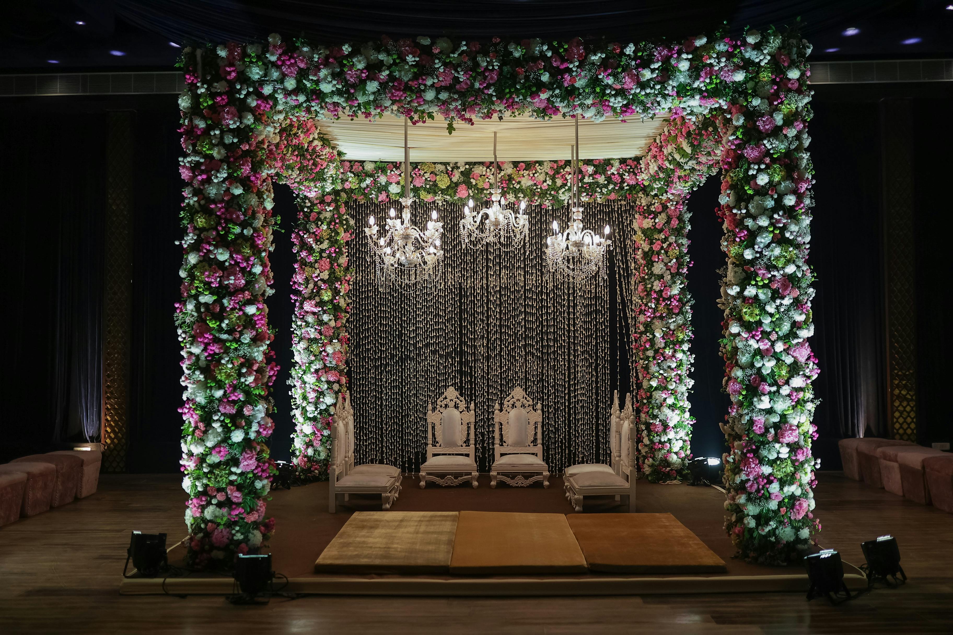 Elegant mandap structure with floral arrangements and draping in a hotel ballroom for a Hindu wedding ceremony