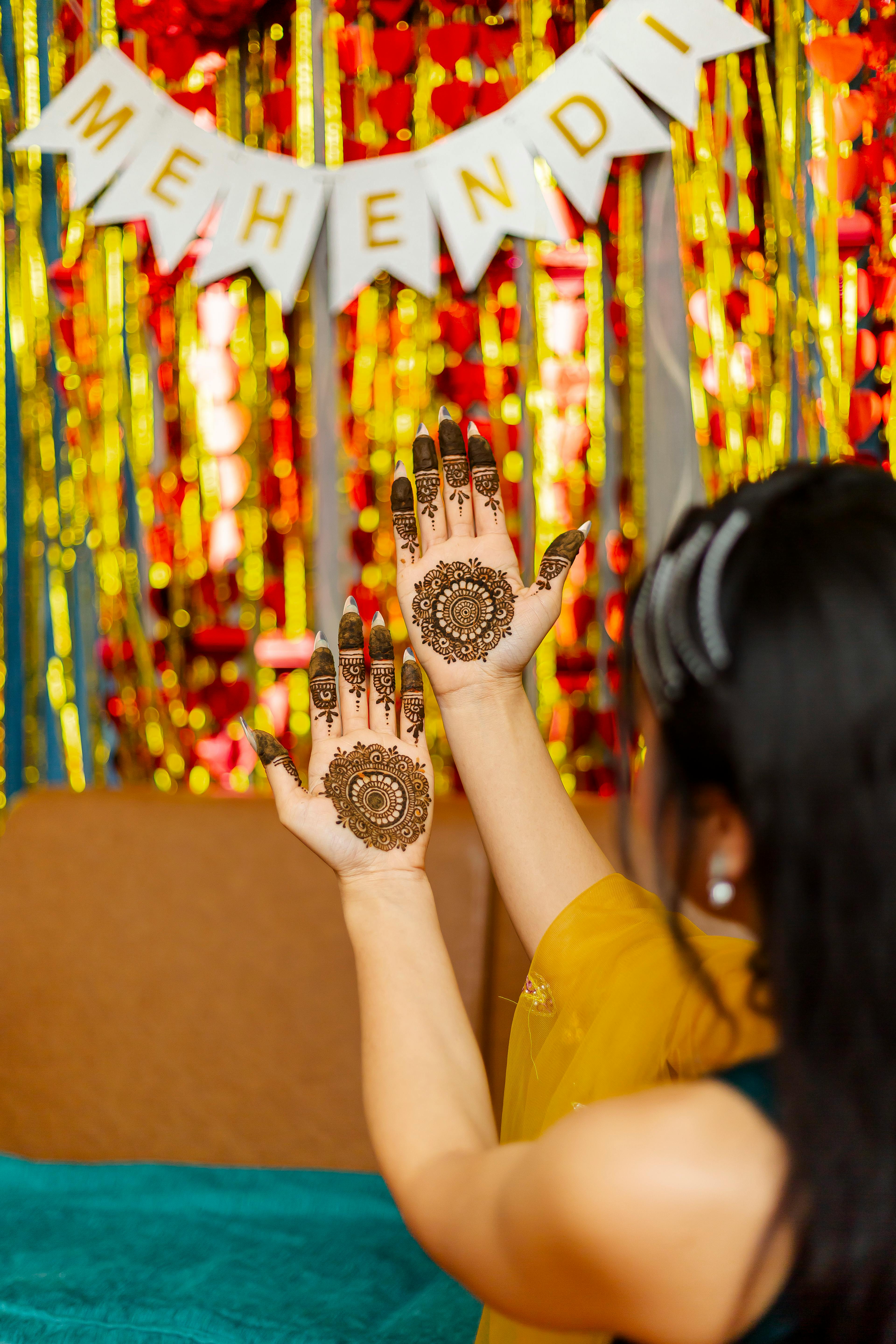 Colorful mehndi ceremony setup with marigold garlands, floor cushions, and string lights in a home setting