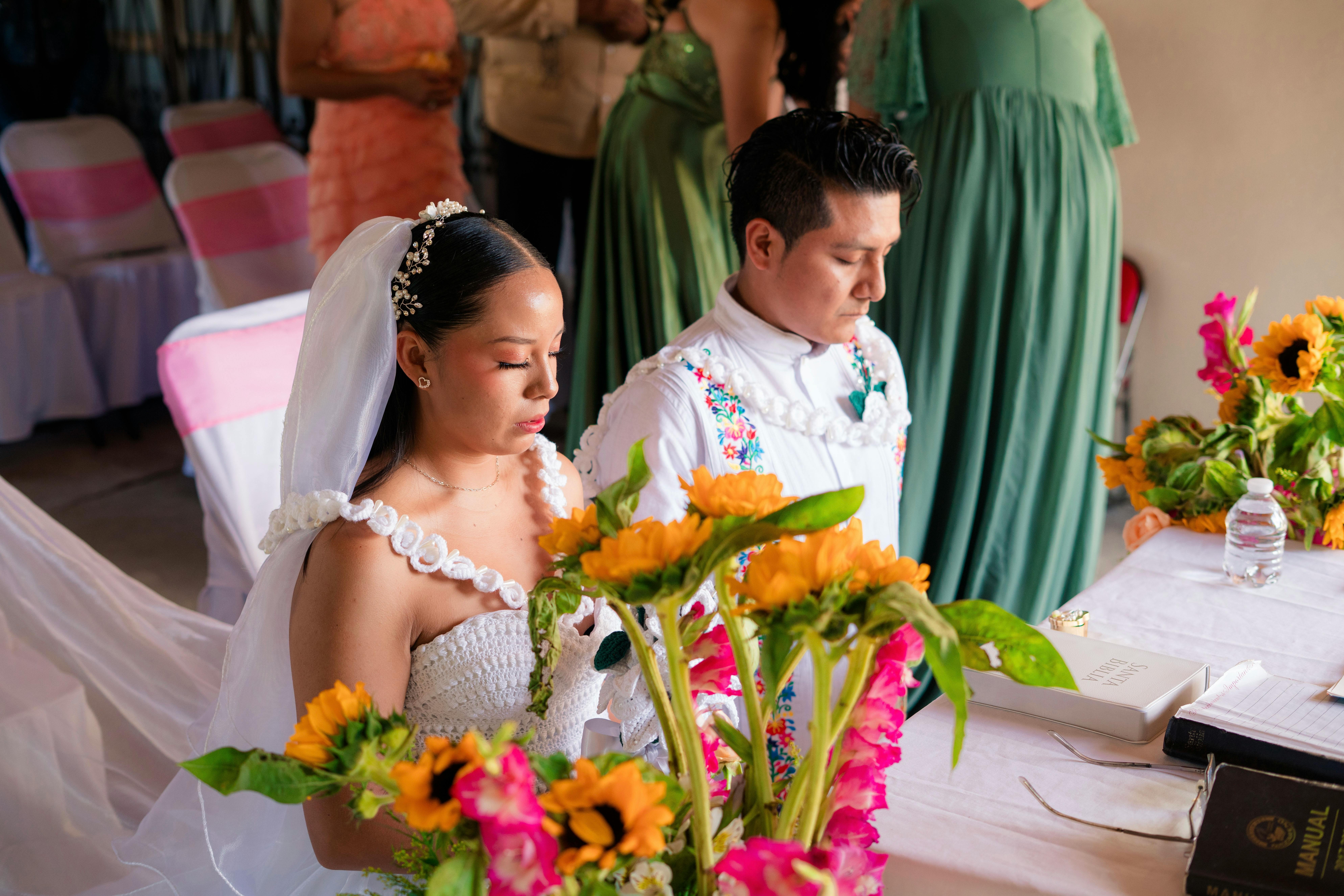 Couple during a Mexican Catholic wedding ceremony with the lazo draped over their shoulders in a figure-eight