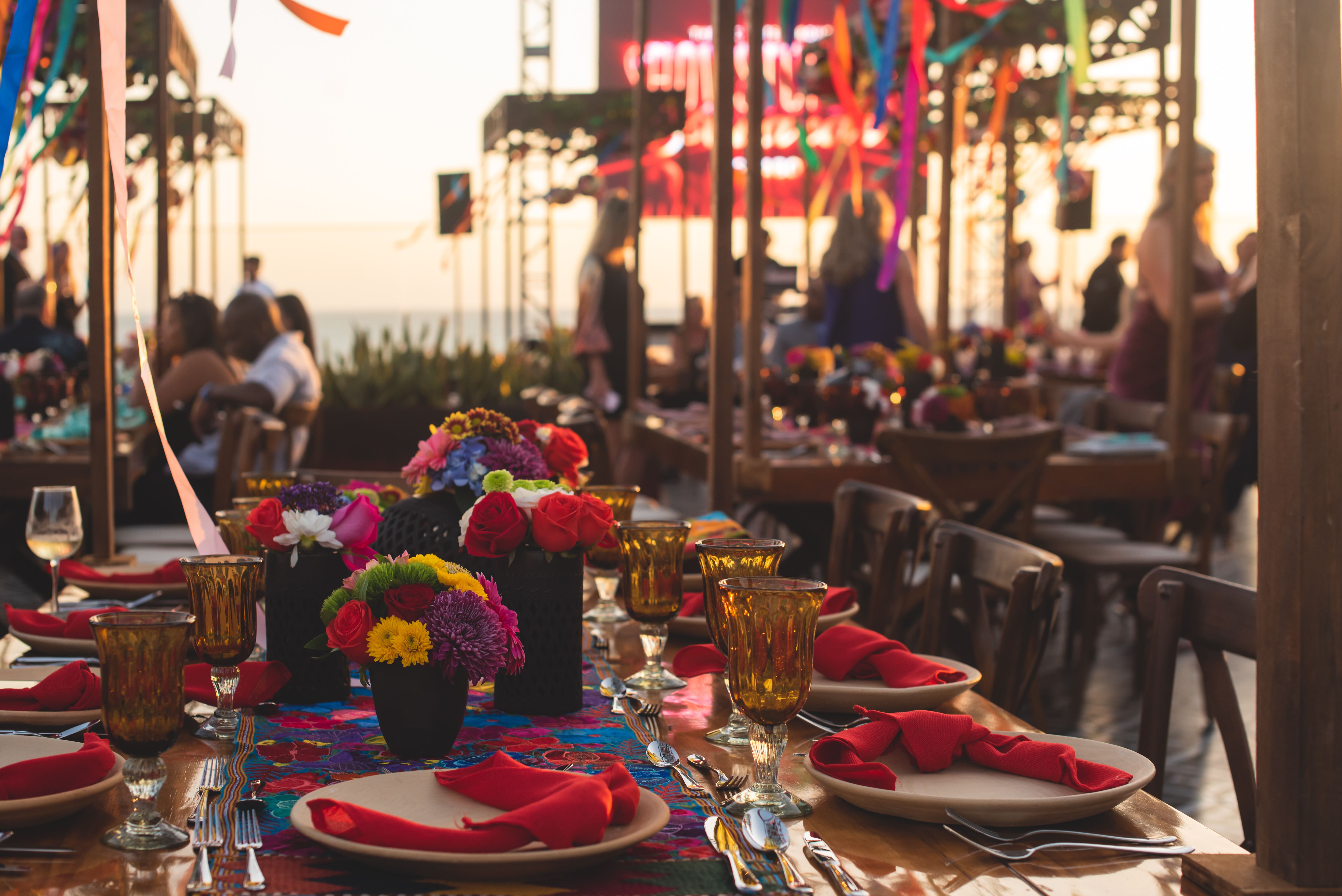 Mexican wedding reception table with colorful papel picado, bright floral centerpieces, and candles